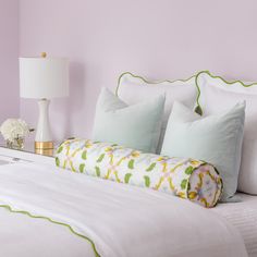 a white bed topped with lots of pillows next to a night stand and table lamp