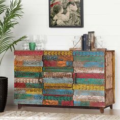 a multicolored chest of drawers next to a potted plant