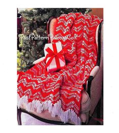 a red and white blanket with a gift wrapped in it on top of a chair next to a christmas tree