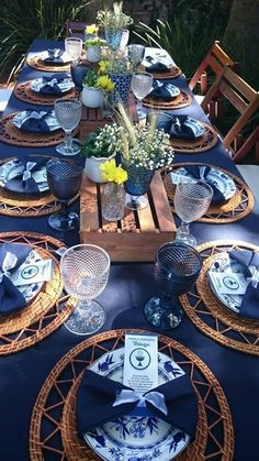 the table is set with blue and white plates, napkins, and vases