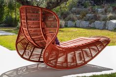 a wicker lounge chair sitting on top of a cement slab next to a tree