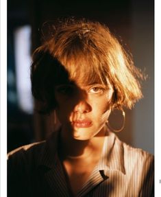 a close up of a person with short hair and earrings on her head, looking at the camera