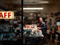 a man standing in front of a sewing machine with an aff sign behind him