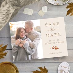 save the date card with an image of two people hugging and surrounded by autumn leaves