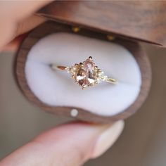 a woman holding an engagement ring in her hand with the inside of it showing two pear shaped diamonds