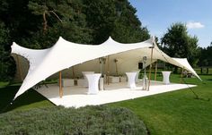 a large white tent sitting on top of a lush green field