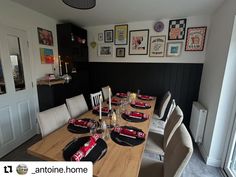 a dining room table with place settings and pictures on the wall