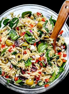 a salad in a glass bowl with a wooden serving spoon on the side, ready to be eaten