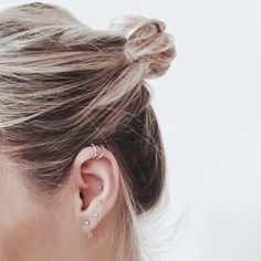 a woman with her hair in a bun and ear piercings is looking at the camera