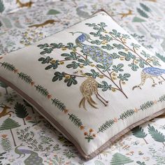 two pillows on top of each other in front of a wallpapered background with animals and trees