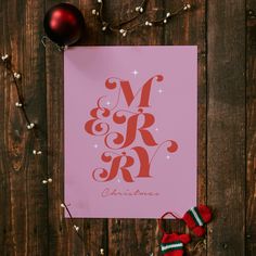 a pink christmas card with the word merry written in red on it next to ornaments