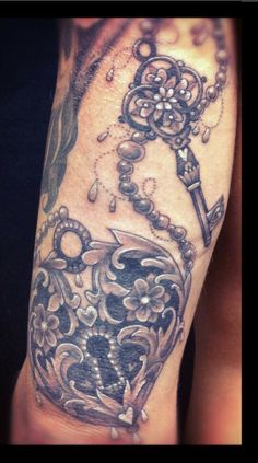 a man's arm with an ornate key tattoo on it