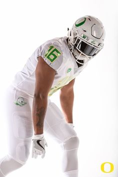 a football player in white and green is posing for a photo with his helmet on