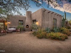 an adobe - style home sits in the desert surrounded by cactus and cacti