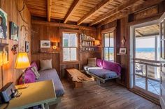 a living room with wood paneling and lots of windows on the wall next to it