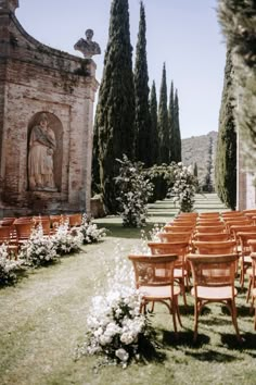 rows of wooden chairs sitting in the middle of a field next to trees and flowers