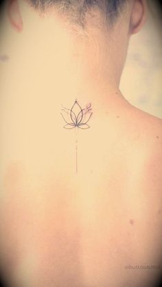 the back of a woman's neck with a flower tattoo on her left side