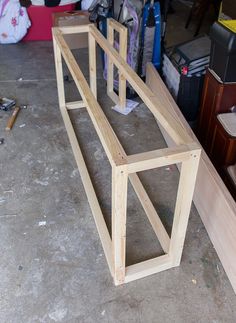 a wooden bench sitting on top of a floor next to a pile of wood planks