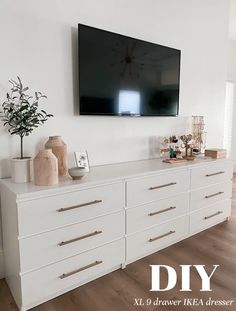 a large flat screen tv mounted above a white dresser