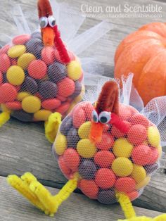 two plastic turkeys sitting on top of a wooden table next to orange pumpkins