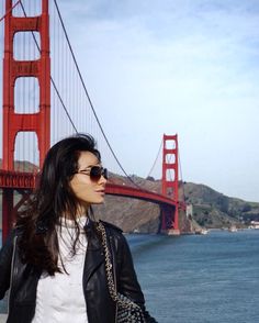 a woman standing in front of the golden gate bridge with her hand on her hip