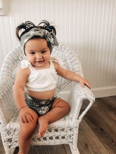 a baby sitting in a wicker chair with a headband on it's head