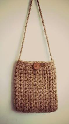 a crocheted purse hanging on a wall with a button in the front and bottom