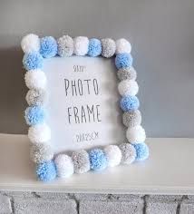 a white and blue frame with pom - poms hanging on the mantle next to a brick wall