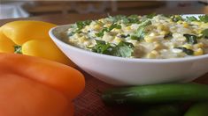 a white bowl filled with corn and vegetables next to tomatoes, bell peppers, and carrots