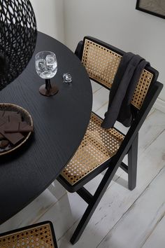 a black table with two chairs next to it and a wine glass on the table