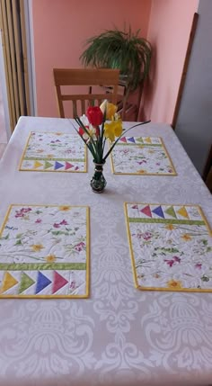 a vase with flowers sitting on top of a table next to two placemats