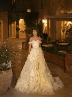 a woman in a white dress is standing outside at night with her hands on her hips