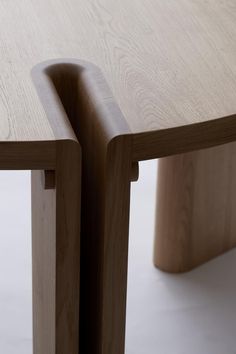 two curved wooden tables sitting next to each other on a white floor with light colored wood