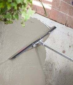 an open umbrella sitting on the ground next to a brick wall and potted plant