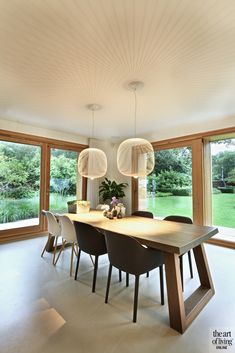 the dining room table is surrounded by modern chairs and large windows with sliding glass doors