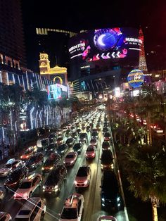 a city street filled with lots of traffic next to tall buildings and neon signs at night