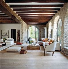 a living room filled with lots of furniture next to a stone wall covered in windows