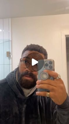 a man taking a selfie in the mirror with his cell phone and wearing glasses