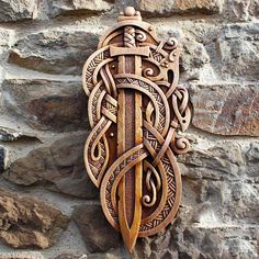 an intricately carved wooden wall hanging on a stone wall