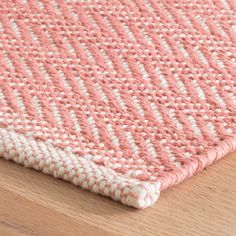 a pink and white rug on top of a wooden floor