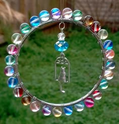 a circular glass ornament hanging from a metal ring with colorful beads on it