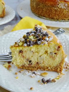 a piece of cheesecake on a plate with a fork next to it and another cake in the background