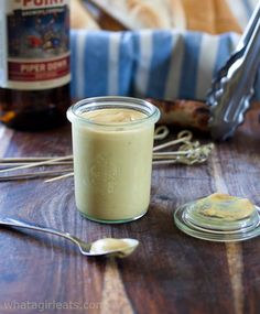 a glass jar filled with liquid sitting on top of a wooden table next to spoons