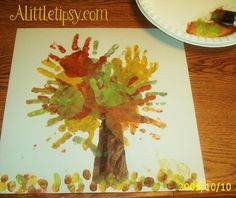 a child's handprinted tree is displayed on a table next to a paper plate