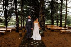 a bride and groom standing in front of trees at their wedding ceremony with lights on them