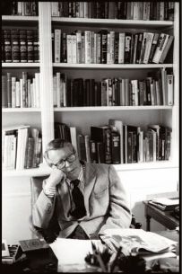 a man sitting at a desk in front of bookshelves