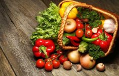 a basket filled with lots of different types of vegetables next to garlic, tomatoes and broccoli