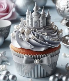 a cupcake with white frosting and a castle on top is surrounded by silver ornaments