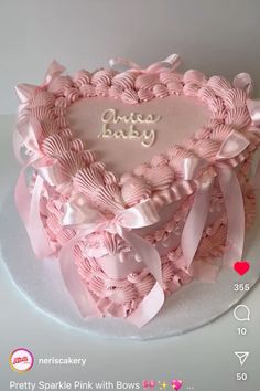 a heart shaped cake with pink bows and name written on the top in white frosting