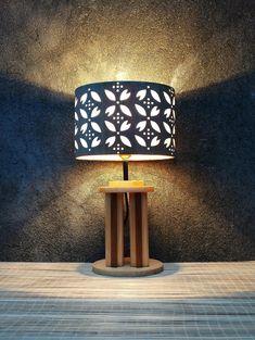 a lamp that is sitting on top of a wooden table in front of a wall